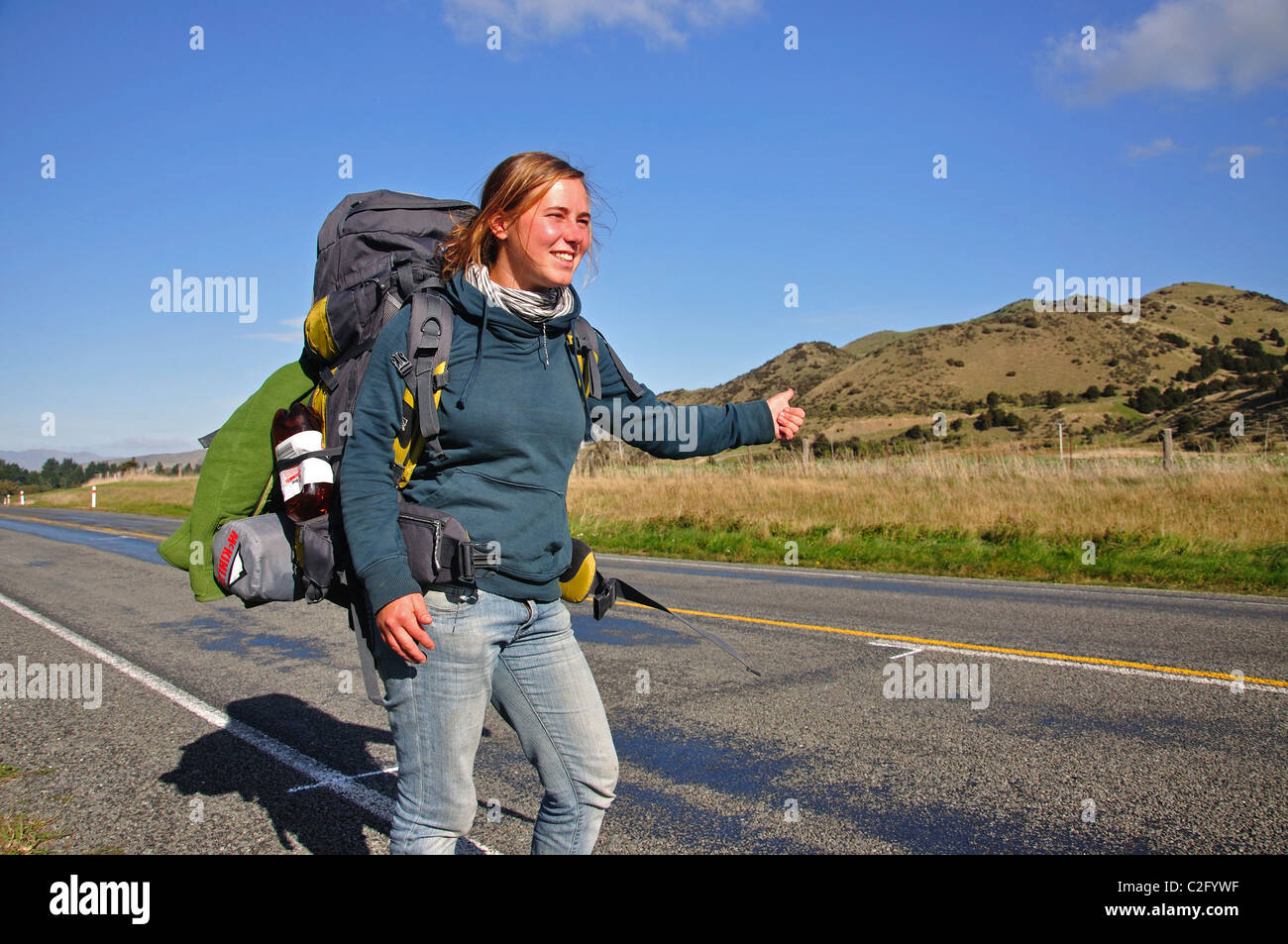 Young female hitchhiker thumbing lift, near Culverden, Canterbury Region, South Island, New Zealand Stock Photo