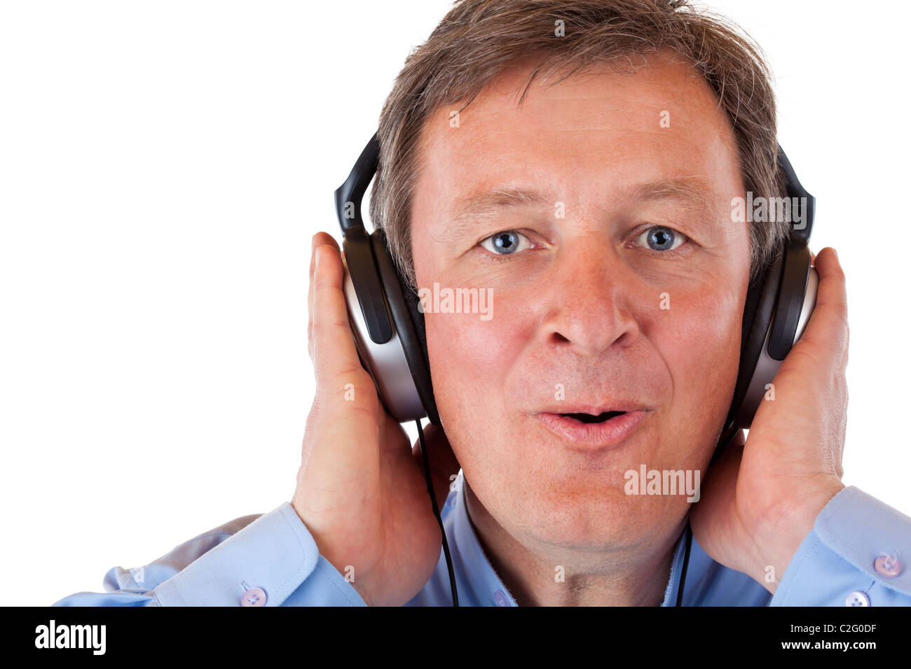 Pensioner with headphones singing happy to mp3 music. Isolated on white background. Stock Photo