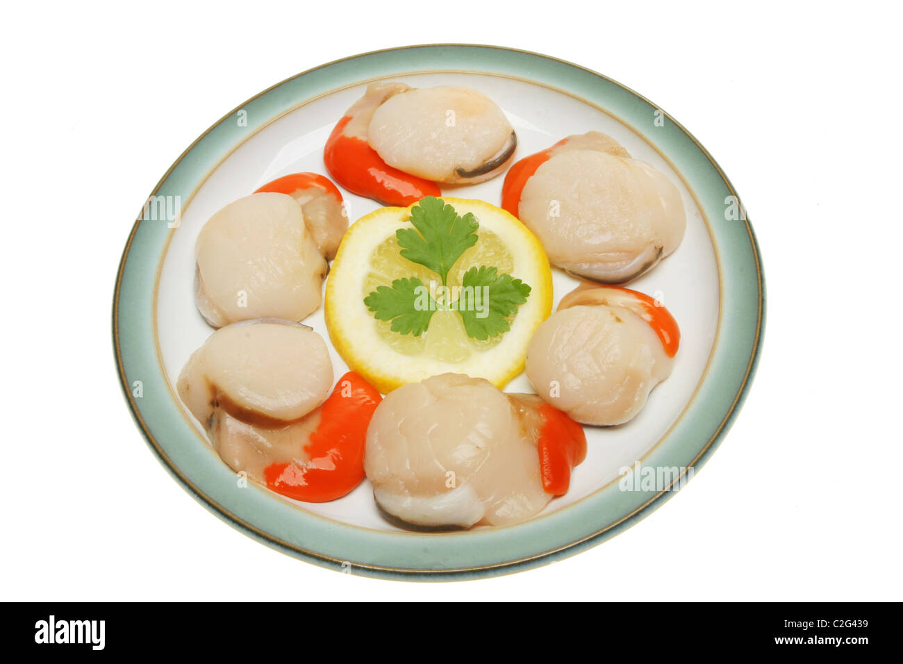 Fresh uncooked scallops on a plate with lemon and parsley Stock Photo