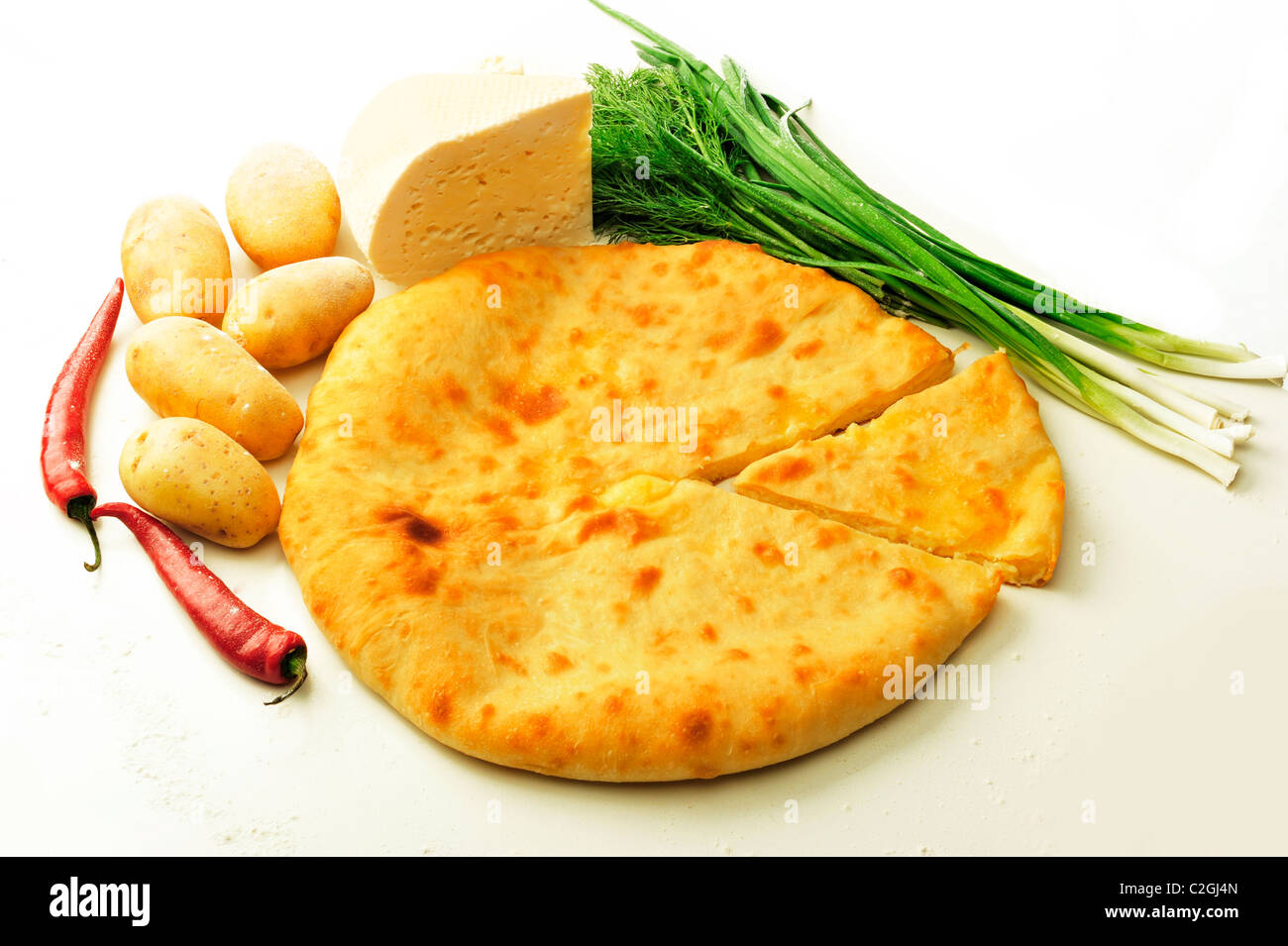 Closeup photo of round ossetian traditional pie and its ingredients on white background Stock Photo