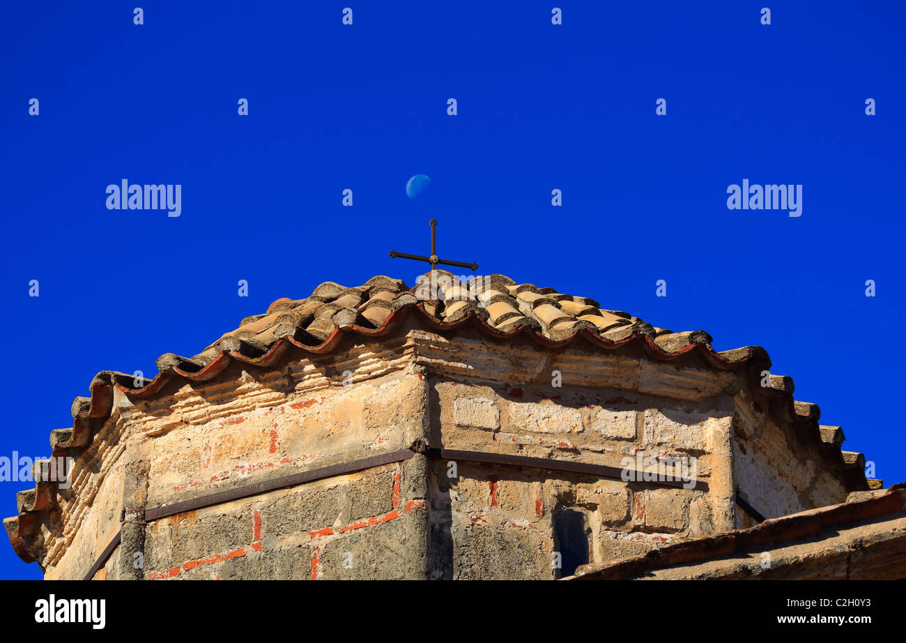 Old Byzantine church roof and cross in Mani, Lakonia, Greece against blue sky and moon Stock Photo