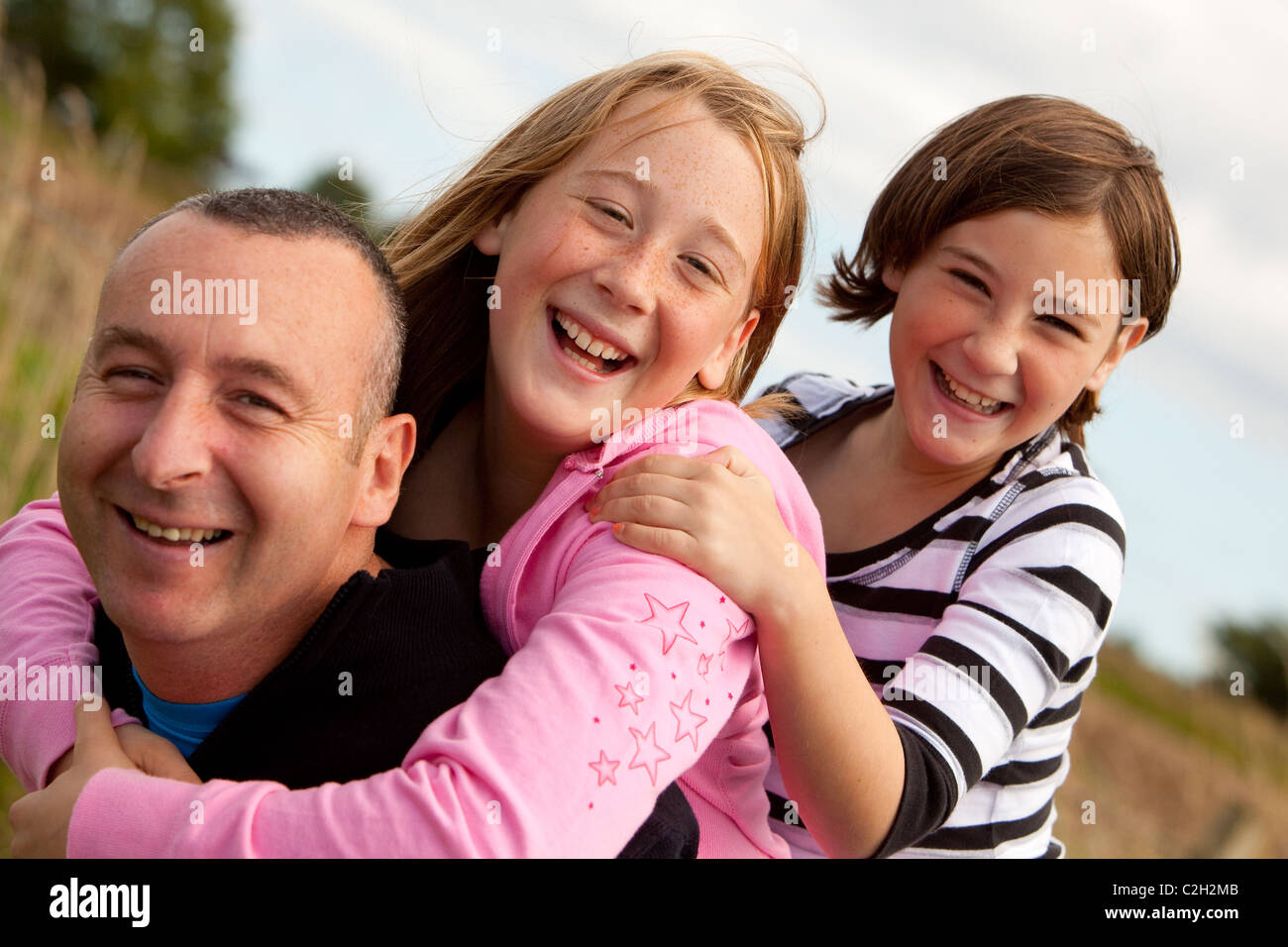 Dad and daughters playing piggy-back on Dad Stock Photo - Alamy