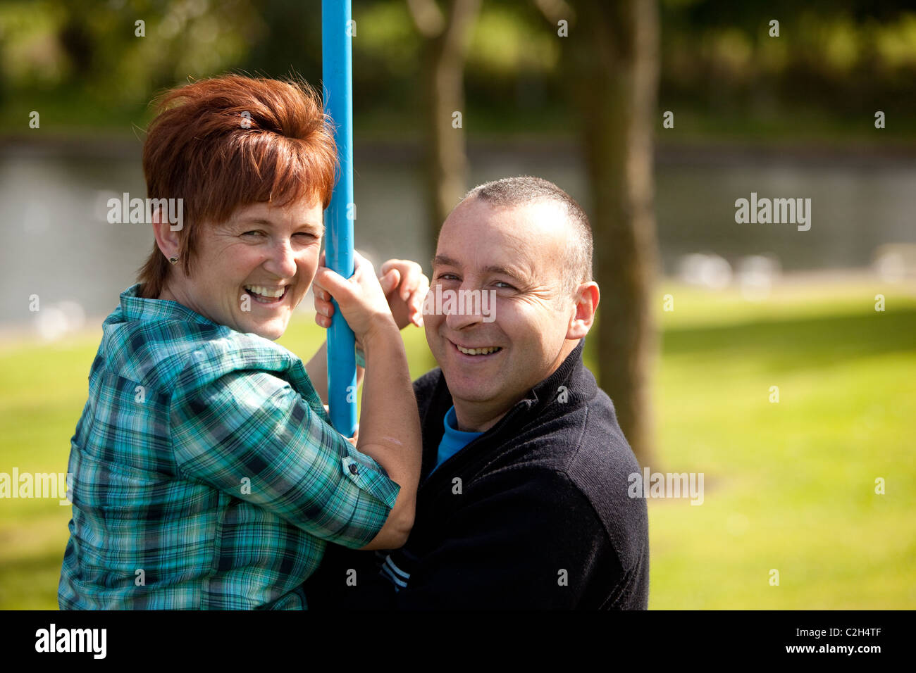 Happy looking Husband and wife couple  playing on children's ride together. Scotland UK Stock Photo