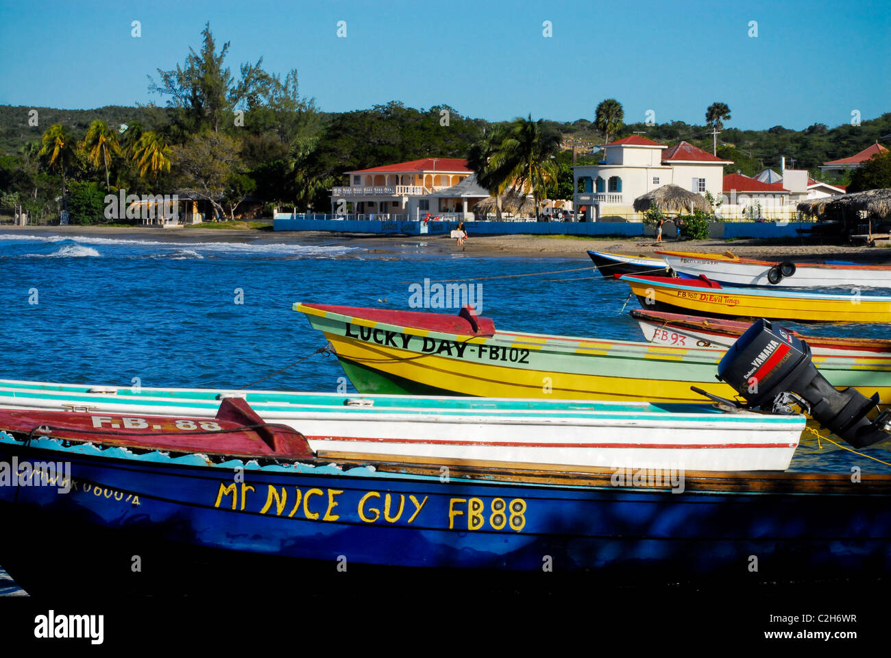 Fishing boats anchored in Frenchman's Bay at Treasure Beach, with Golden Sands Beach Resort in background, St Elizabeth, Jamaica Stock Photo