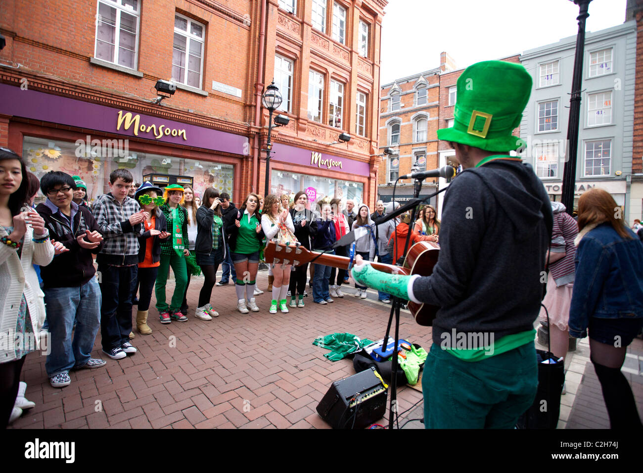 St Patricks Day Revellers on Grafton Street, Dublin, Ireland watching a band play music and sing some songs Stock Photo