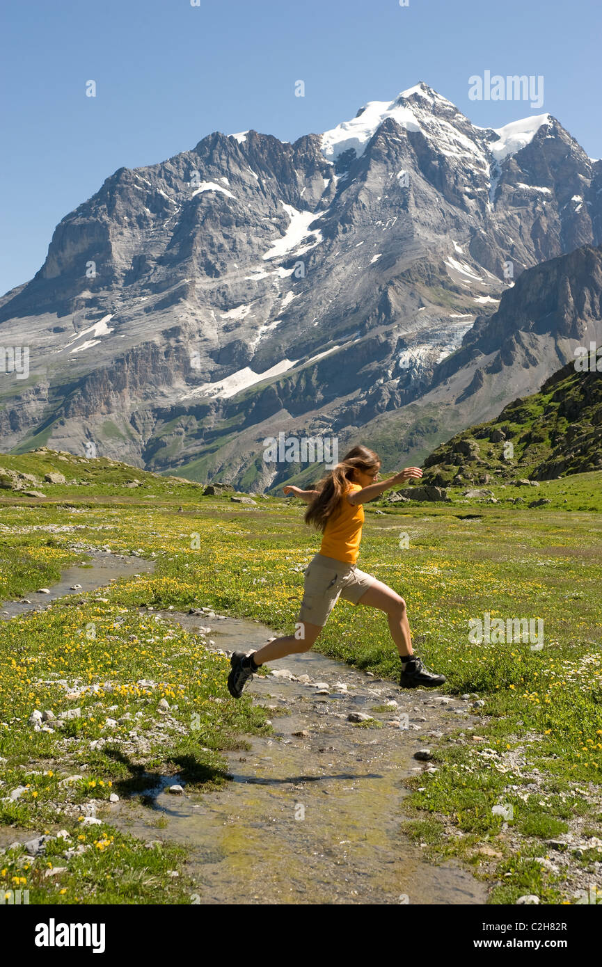A woman jumping over a mountain stream, Lauterbrunnental, Switzerland Stock Photo
