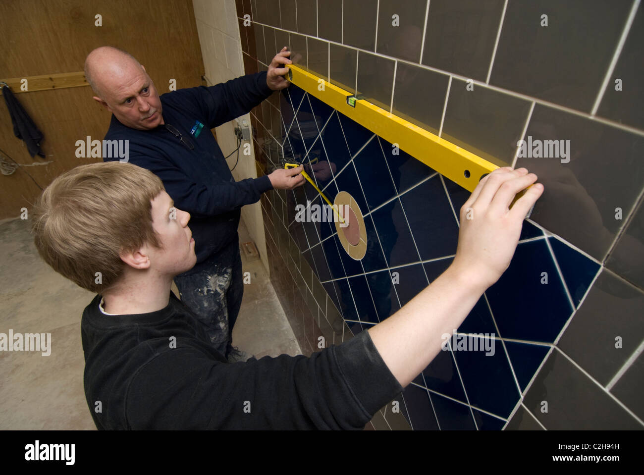 Teaching an apprentice wall tiling Stock Photo Alamy