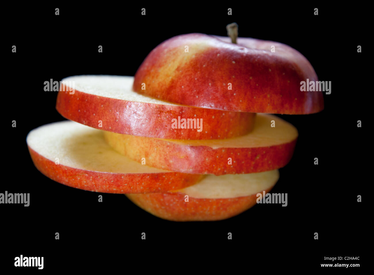 An apple cut into slices and stacked on a black background Stock Photo