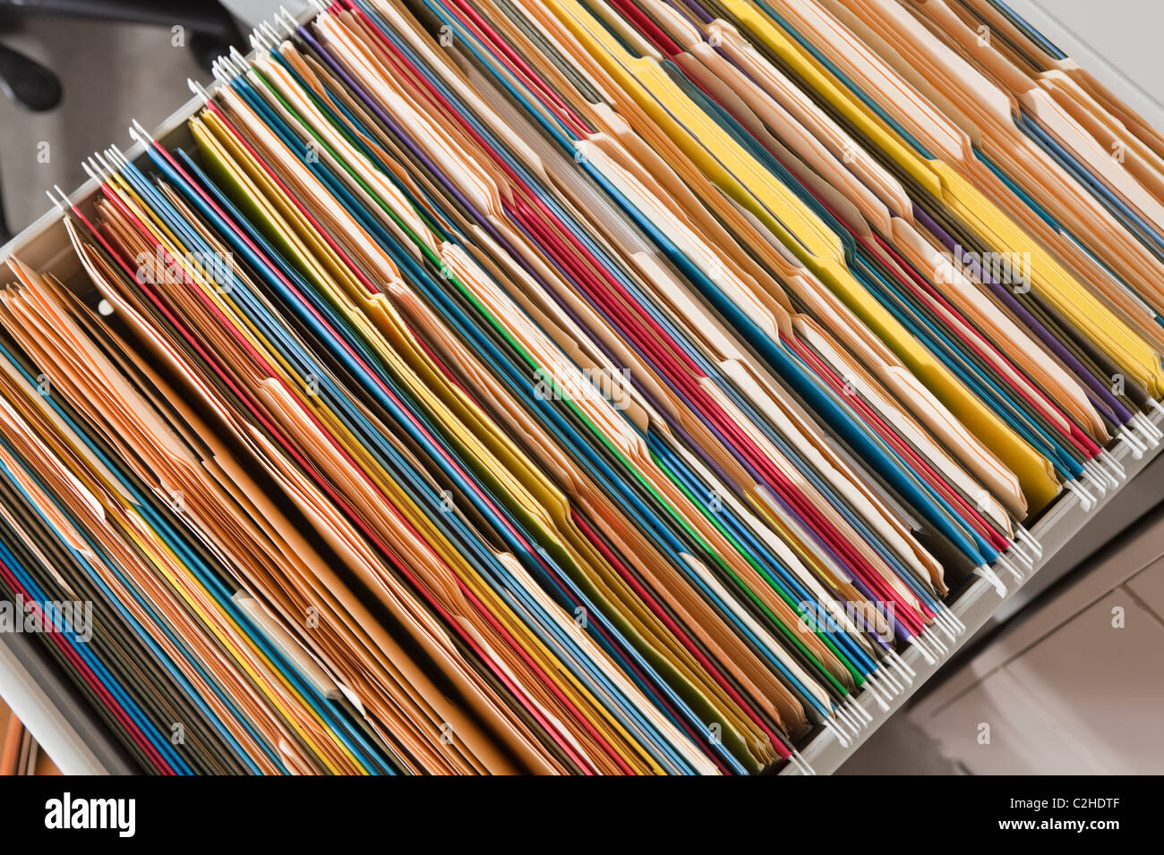 Packed file cabinet with colorful hanging file folders. Stock Photo
