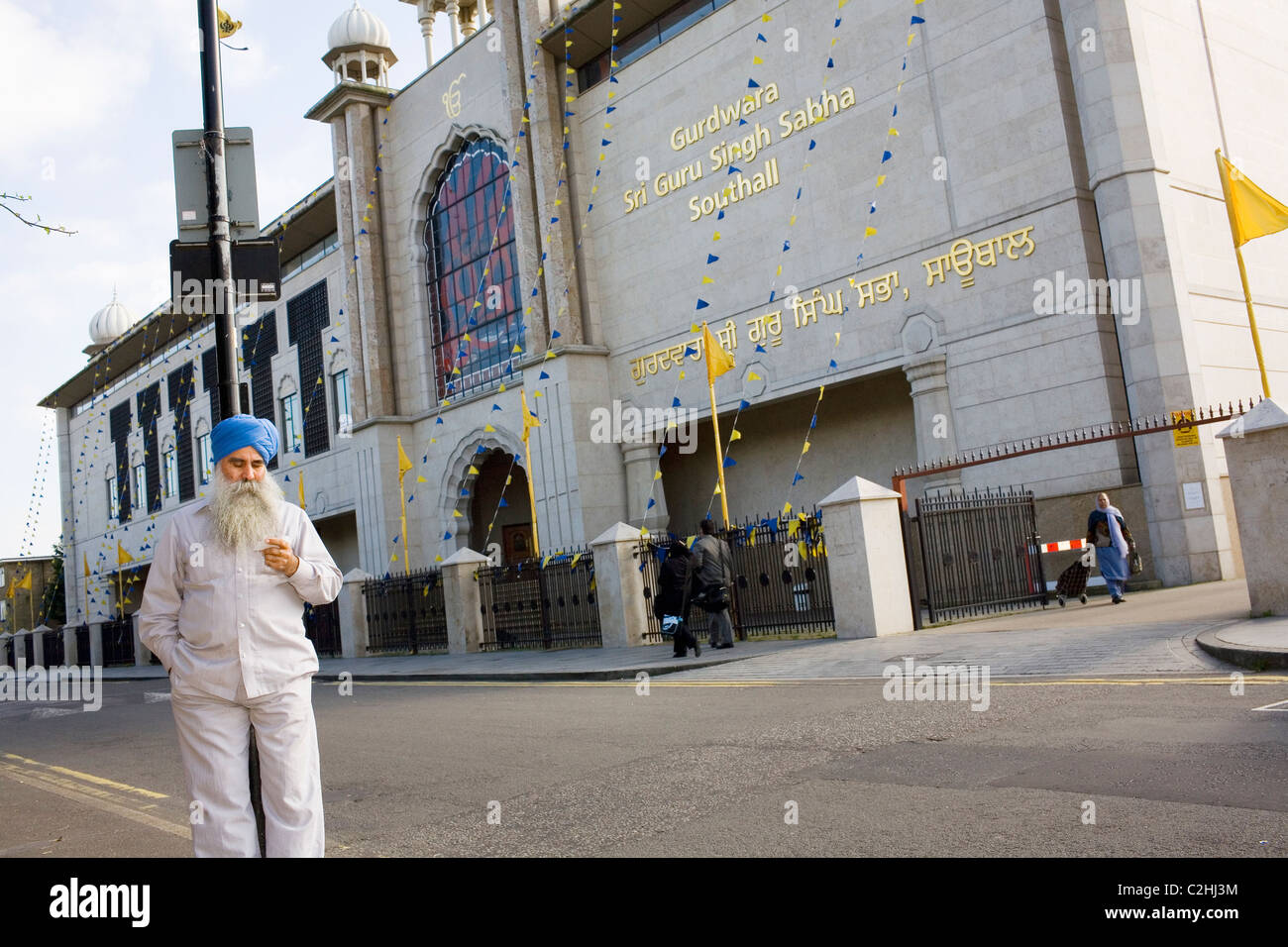 A Sikh man leans on a lamp post outside a temple in Southall, a west London suburb. Stock Photo