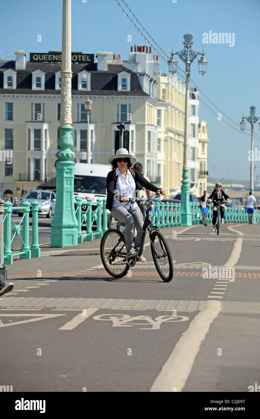 Woman riding bicycle wearing a sun hat in cycle lane during hot