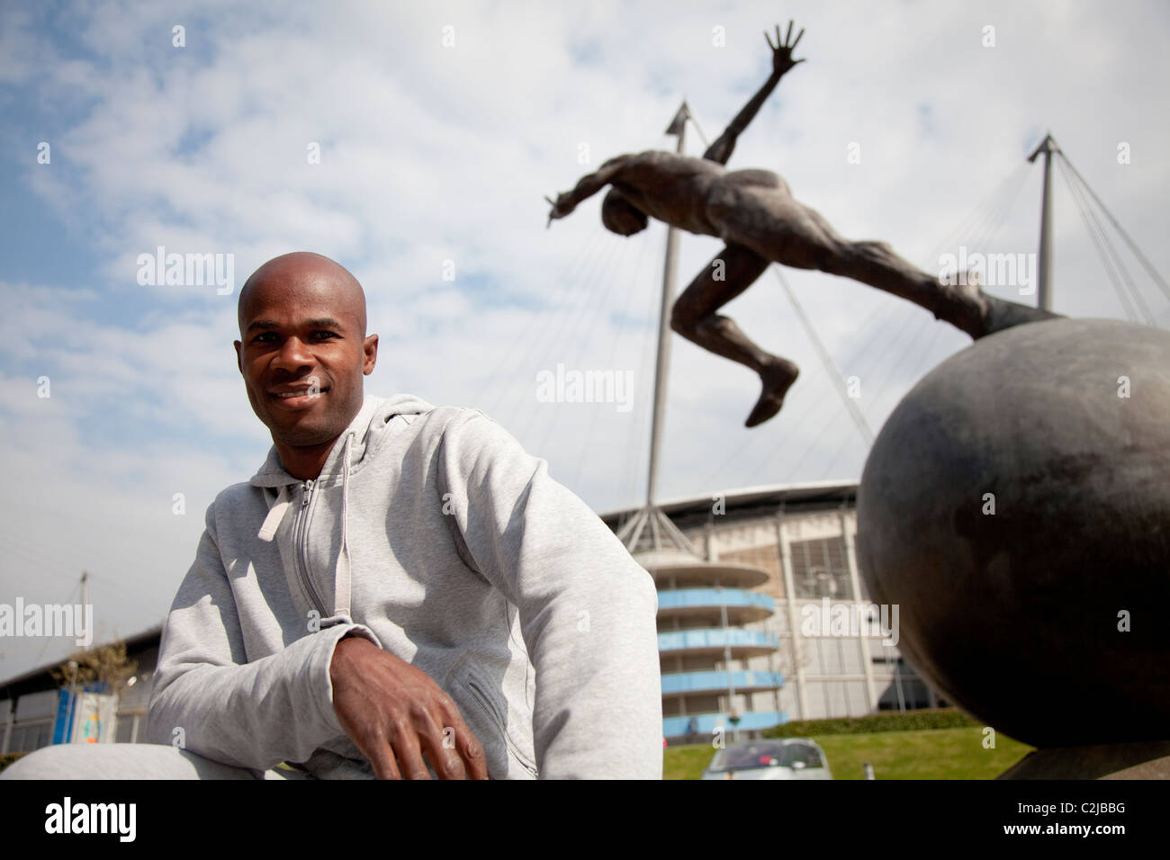 Kim Collins stands by the statue of a sprinter modeled on himself after his performance in the Manchester Commonwealth games Stock Photo