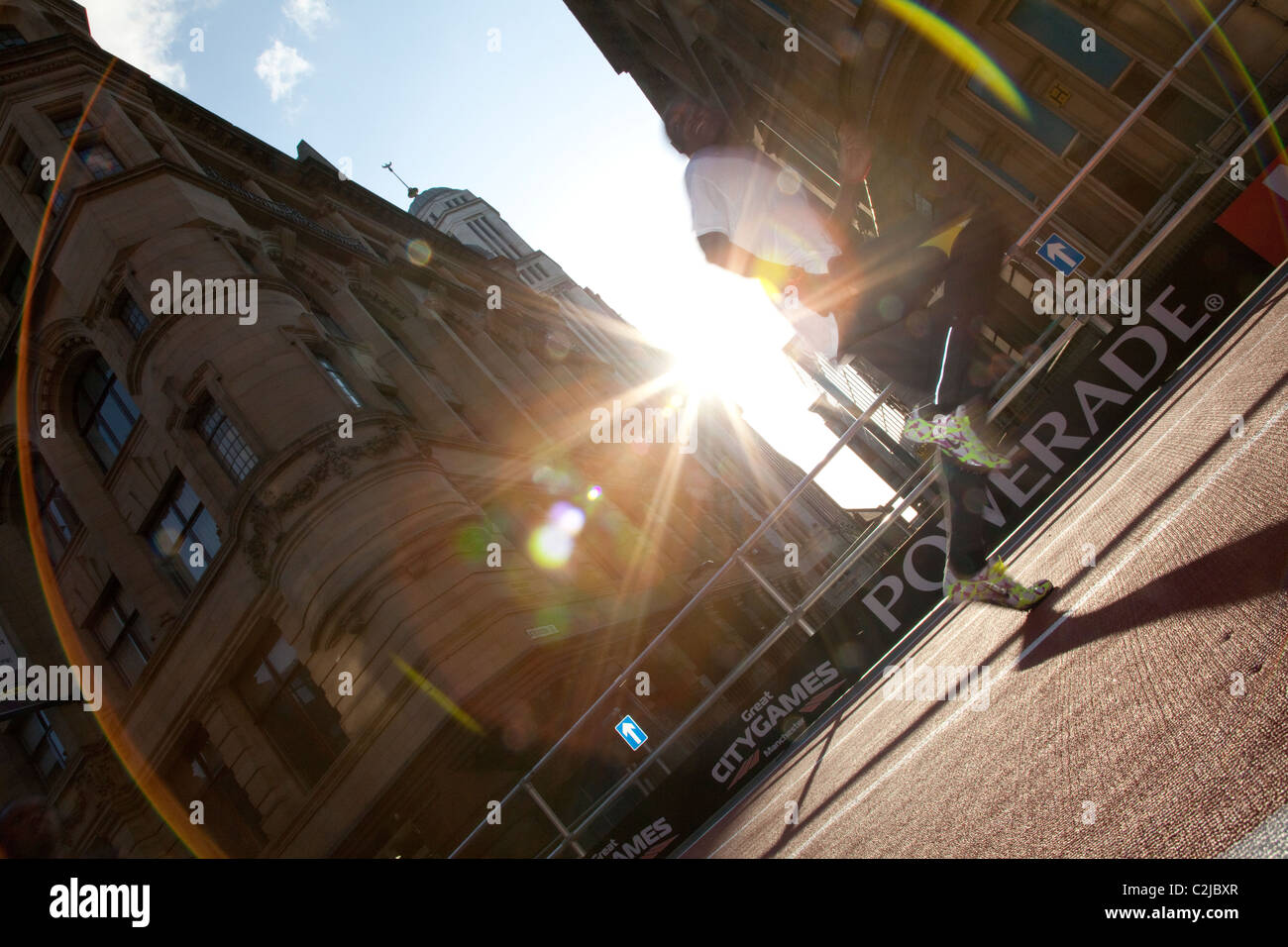 A sprinter catches the light on Deansgate, Manchester, as he warms up for the Great City Games 2010, on a temporary track. Stock Photo