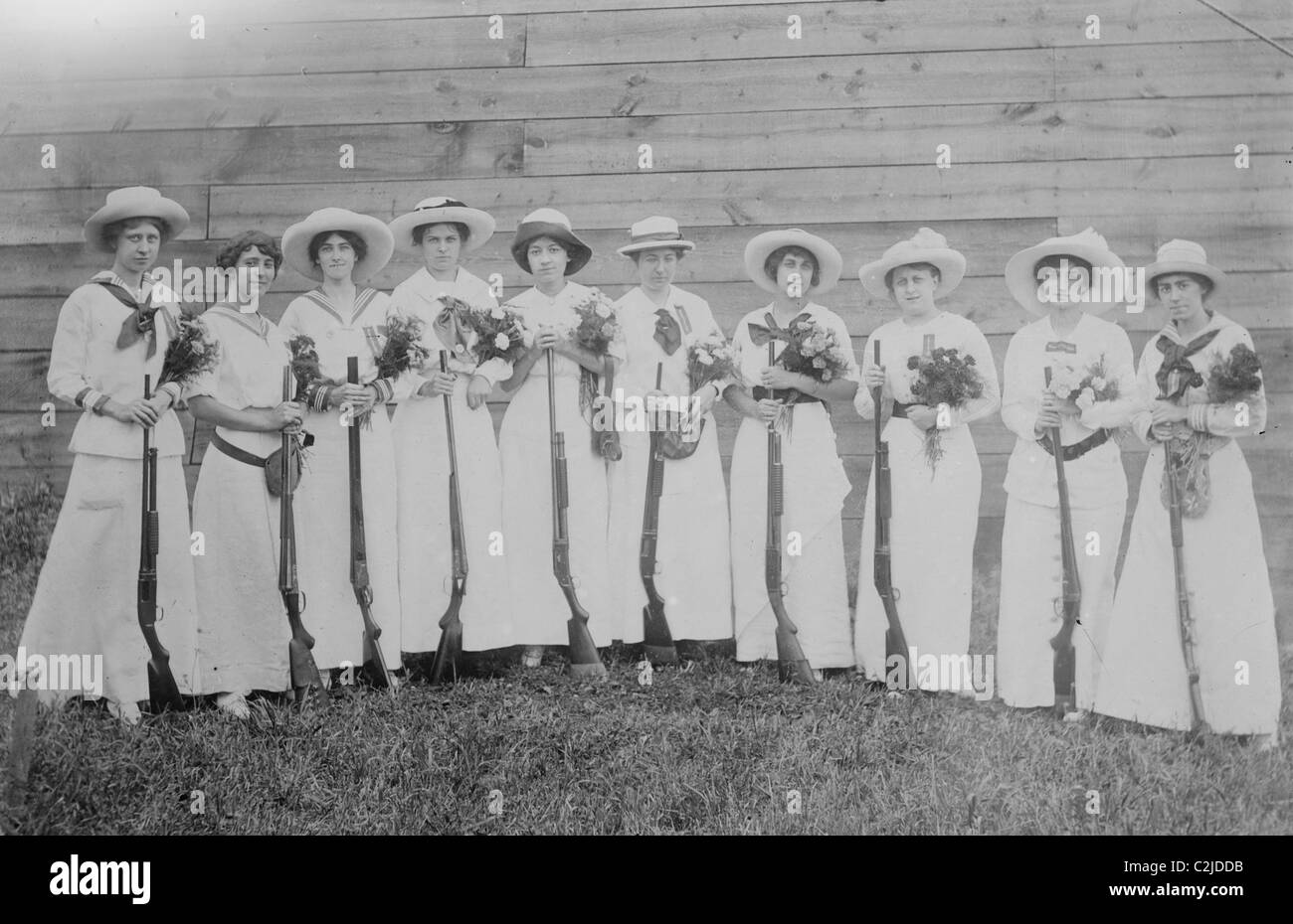 Nemours Women's Trap shooting Club in elegant dress hold both nosegays and rifles. Stock Photo