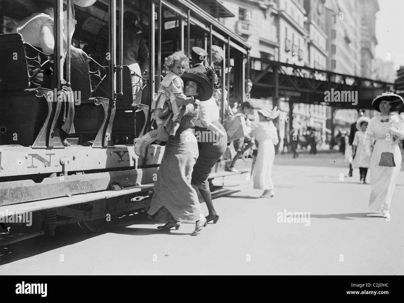 Woman lifts child off of an open sided Trolley Car on New York's