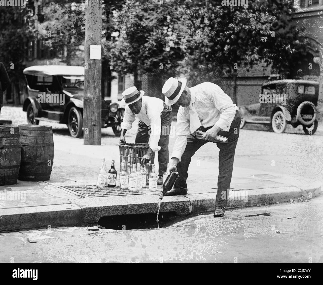 Agents Pouring liquor down a sewer on the Street Stock Photo
