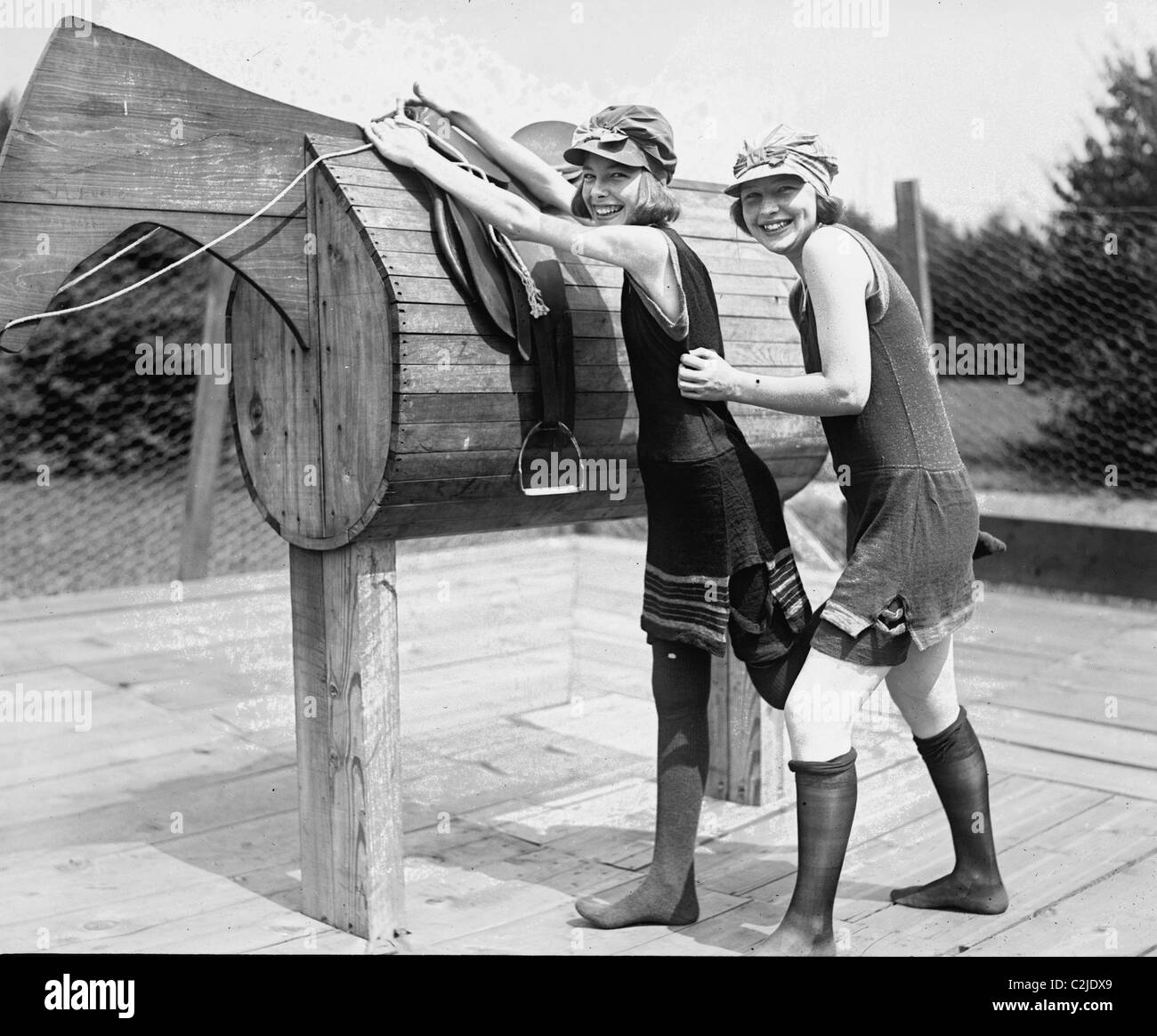 Girl is Helped by Friend to Mount a wooden Polo Dummy Horse Stock Photo