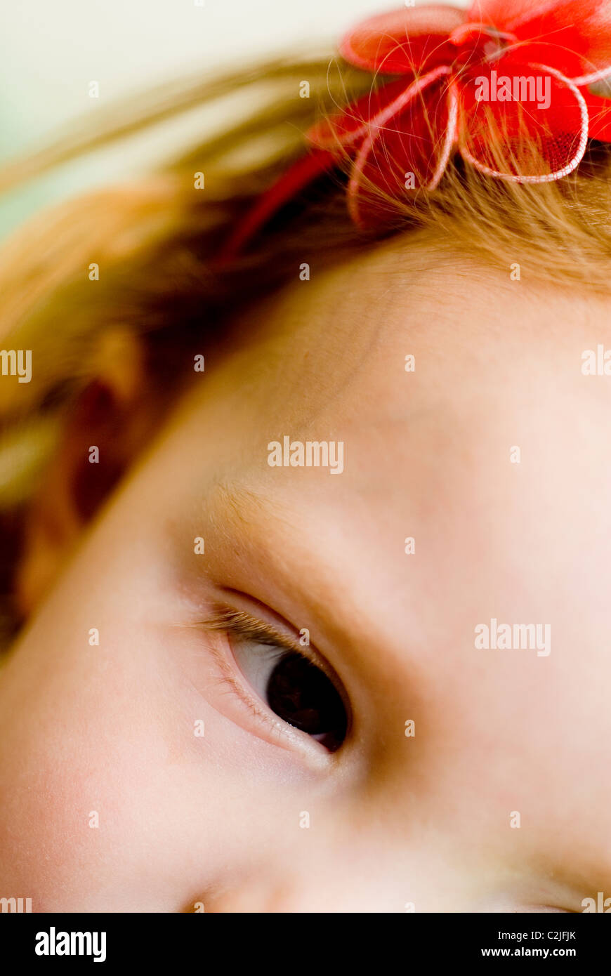 Close up of child with red hair and red flowered head band. Stock Photo