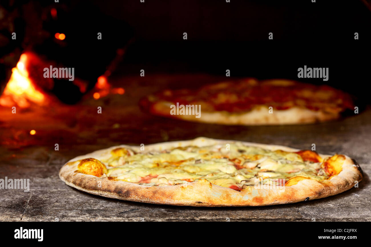 delicious pizza baking in wood fired oven Stock Photo