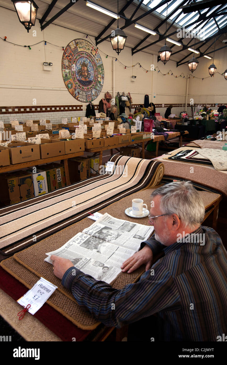 UK, England, Staffordshire, Leek, Trestle Market, stallholder reading newspaper at start of day Stock Photo