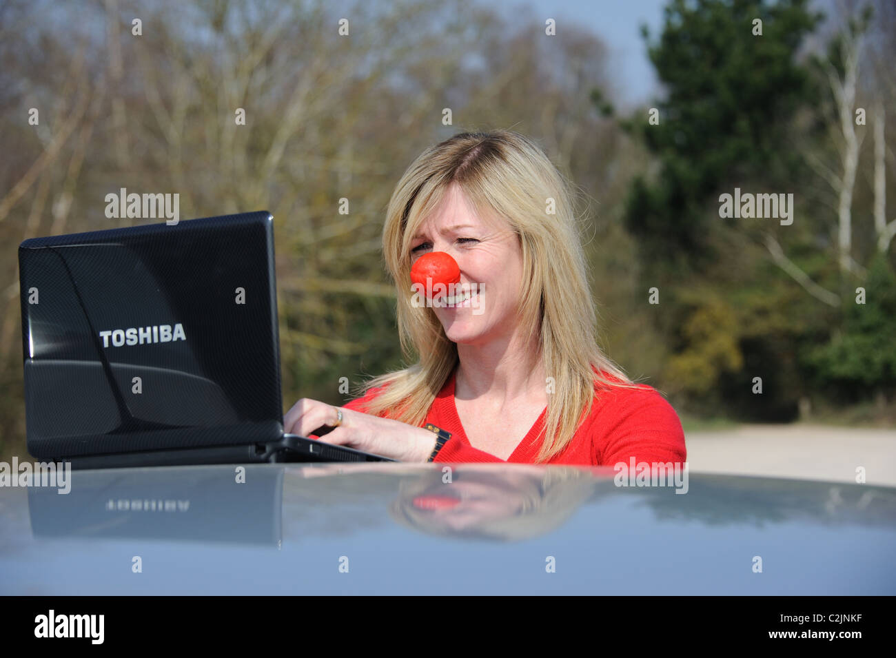 Woman using a netbook computer and wearing a charity red nose Stock ...