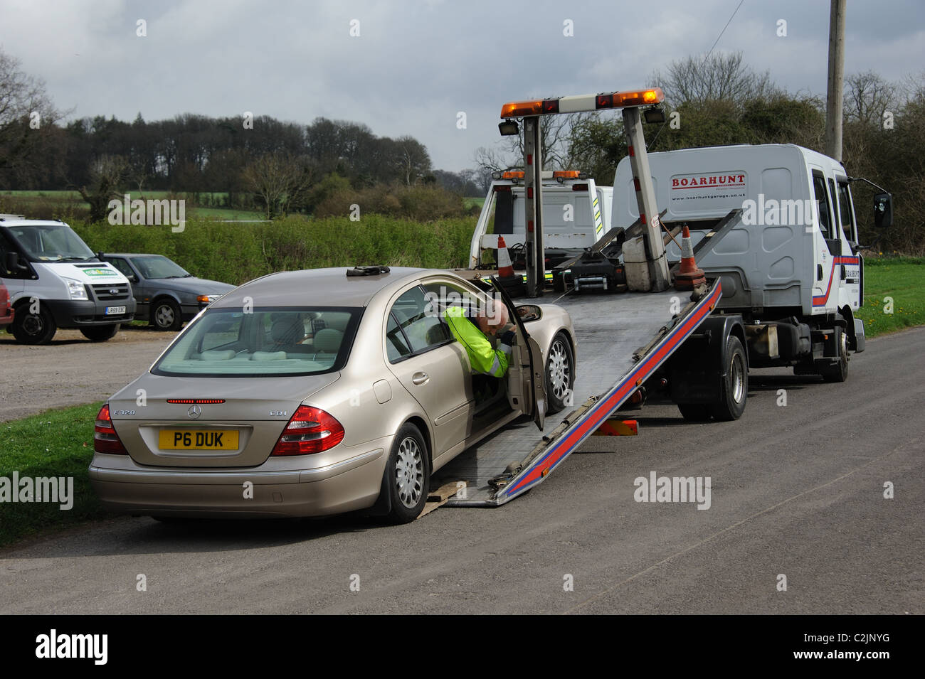 Vehicle roadside recovery truck with a mechanic loading a Mercedes car in Micheldever Hampshire UK Stock Photo