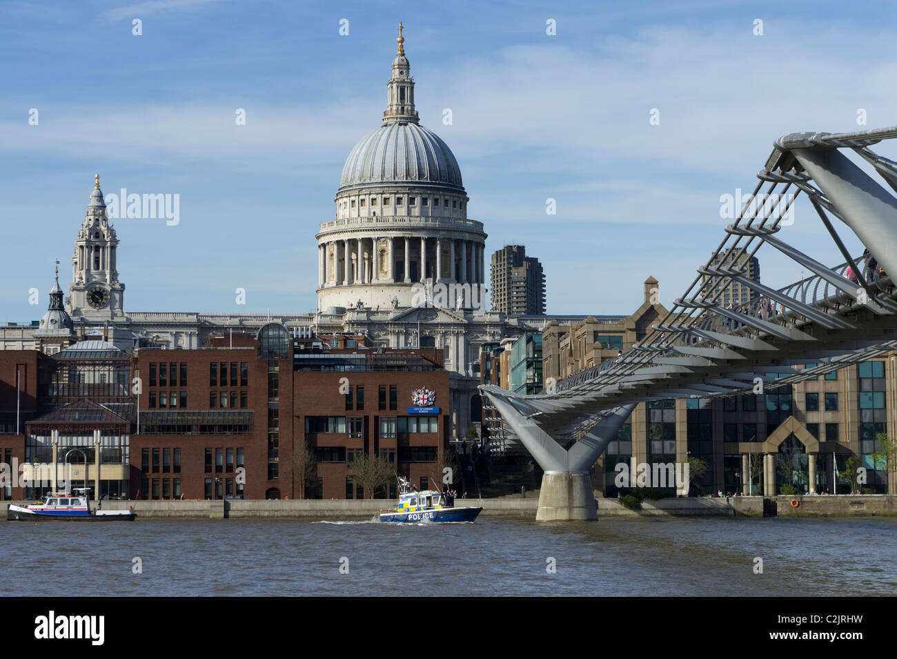 Metro police boat passing by Millennium Bridge with St. Paul's Cathedral in the background, London, England, UK Stock Photo