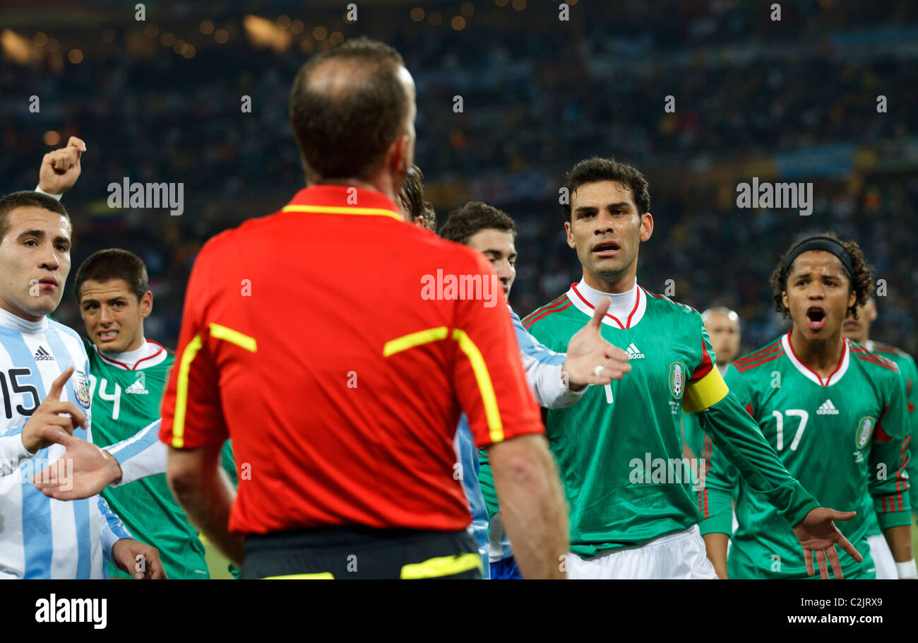 Mexico and Argentina players confront assistant referee Stefano Ayroldi after a controversial Argentina goal at 2010 World Cup. Stock Photo
