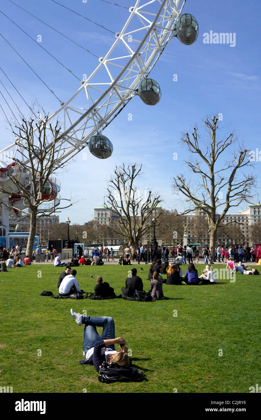 Group of people enjoying the sun at Jubilee Gardens next to the London Eye, London, England, UK Stock Photo