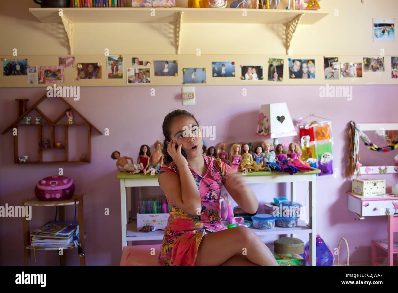 7-years old girl talks on the cell phone in her bedroom. Nova Friburgo, Rio de Janeiro State, Brazil. Stock Photo