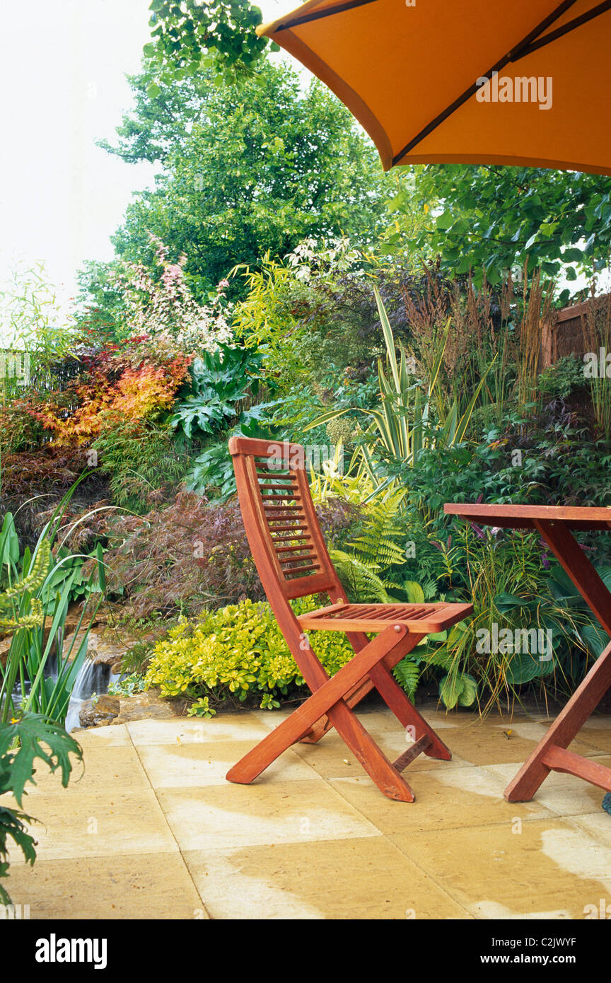 Wooden chair and table on a patio next to a water feature Stock Photo ...