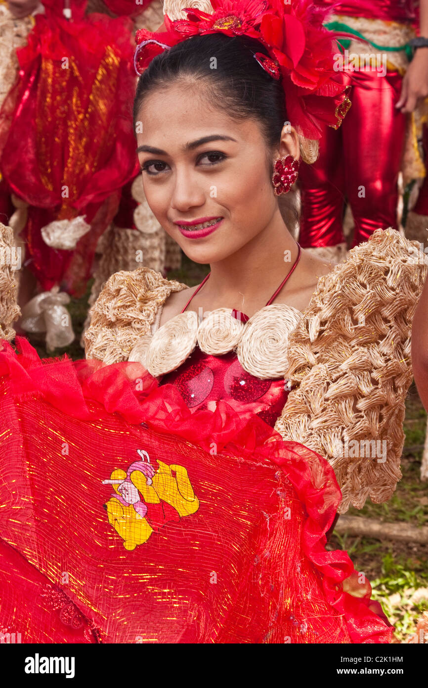 A portrait of a Filipina woman with a red floral head dress holding a red, lacy umbrella. Stock Photo
