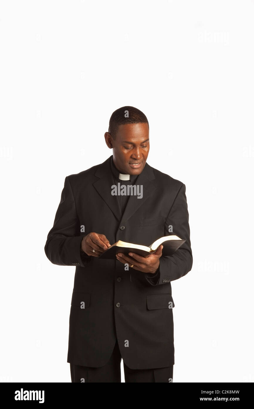 A Man Wearing A Clerical Collar And Reading From His Bible Stock Photo