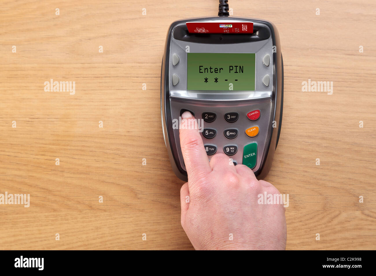 Photo of a womans hand typing her number into a Chip and Pin credit card terminal, the card in the machine is a mock up. Stock Photo