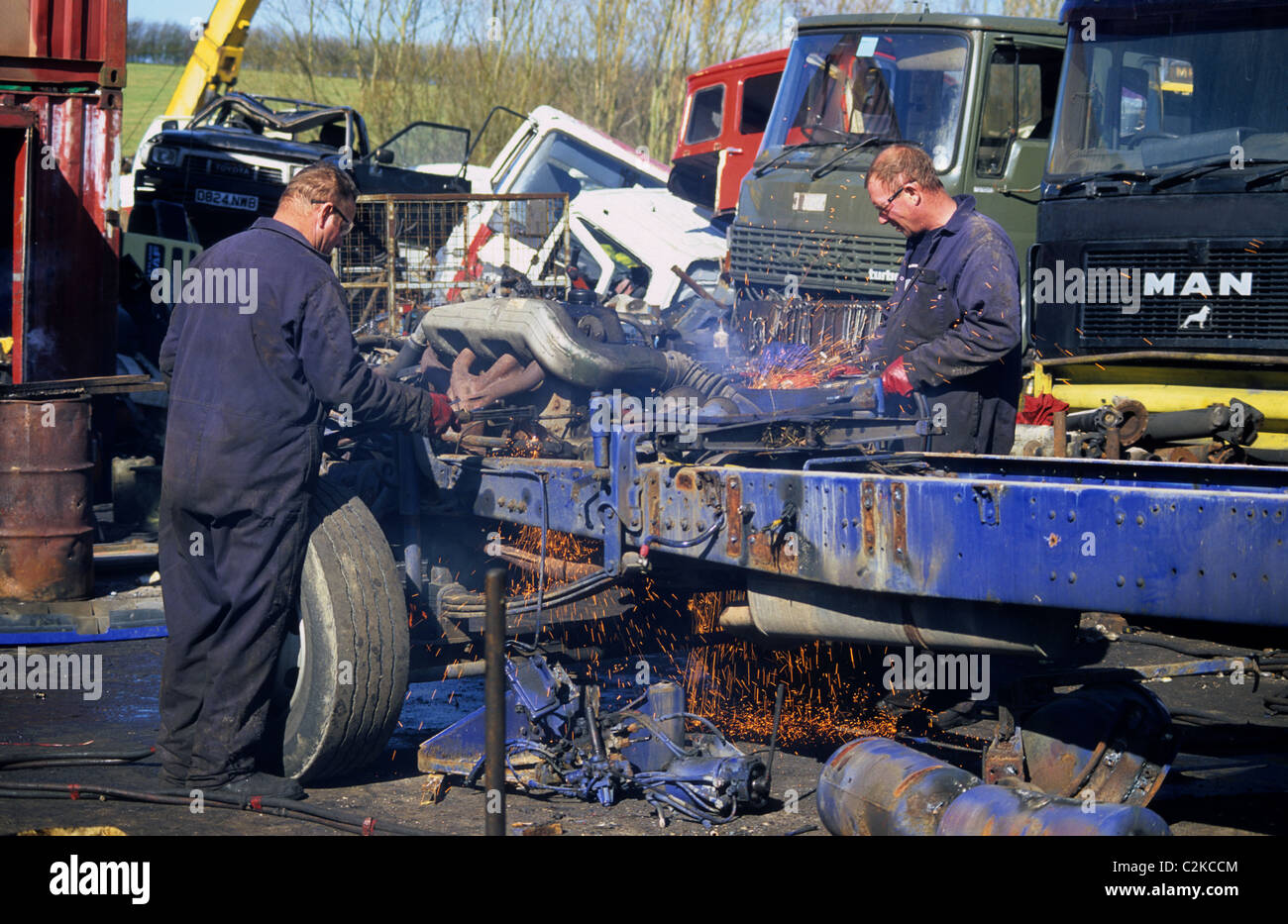 workmen using cutting torches to dismantle lorry in scrapyard uk Stock Photo