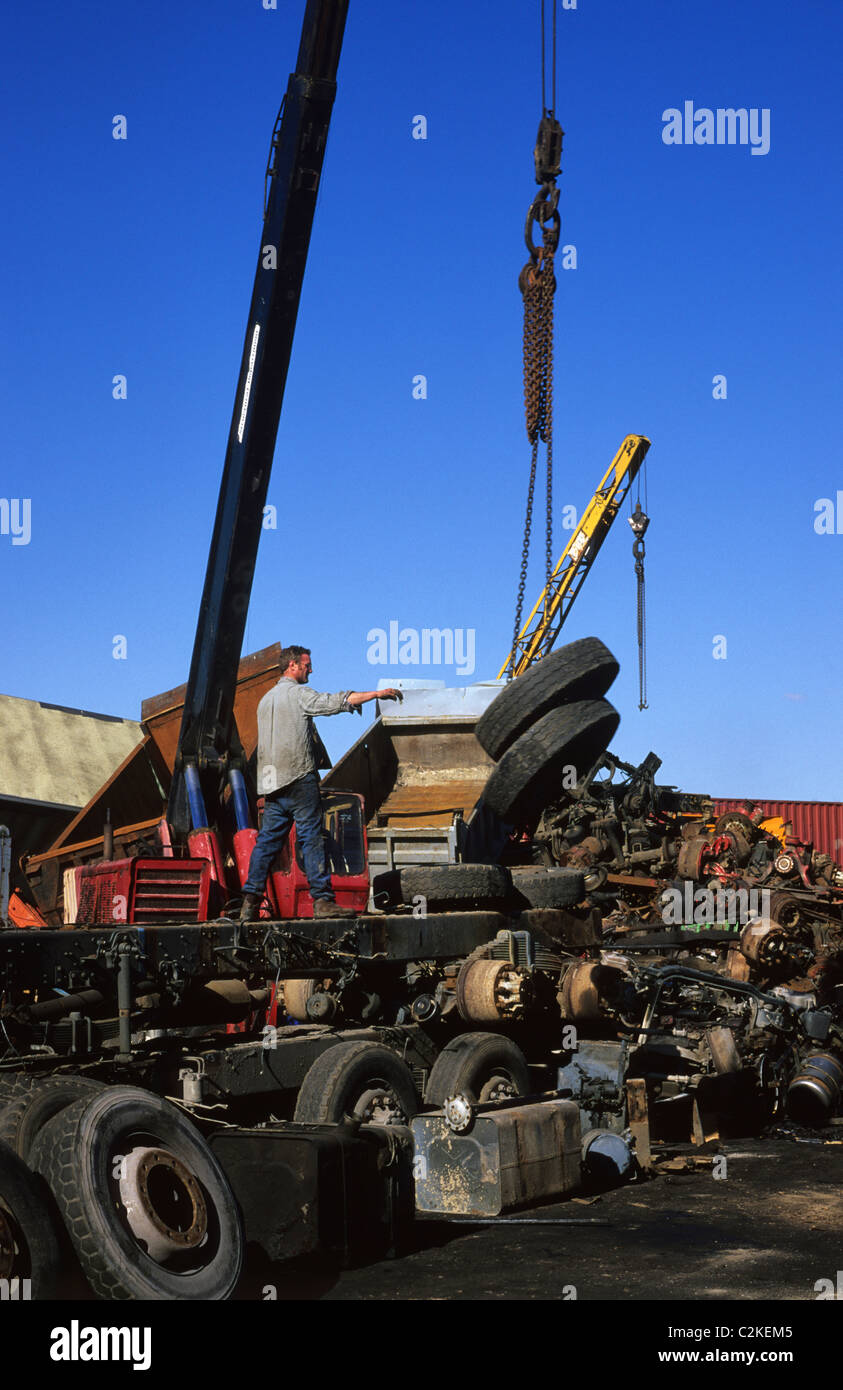 crane lifting lorry wheels from lorry chassis for recycling at scrapyard uk Stock Photo