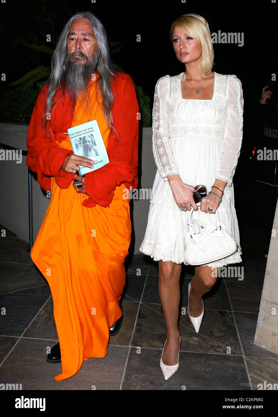 Paris Hilton is seen out with a Shaman who is showing her a book titled 'The Path to the Painted