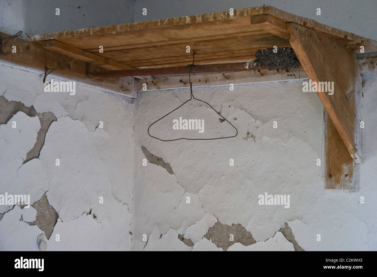 A Wooden Corner Shelf With A Hanger Mounted On A Wall With Peeling