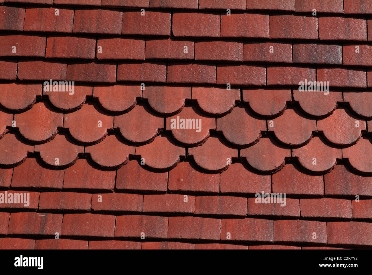 Backgrounds - straight and scalloped red clay roof tiles Stock Photo
