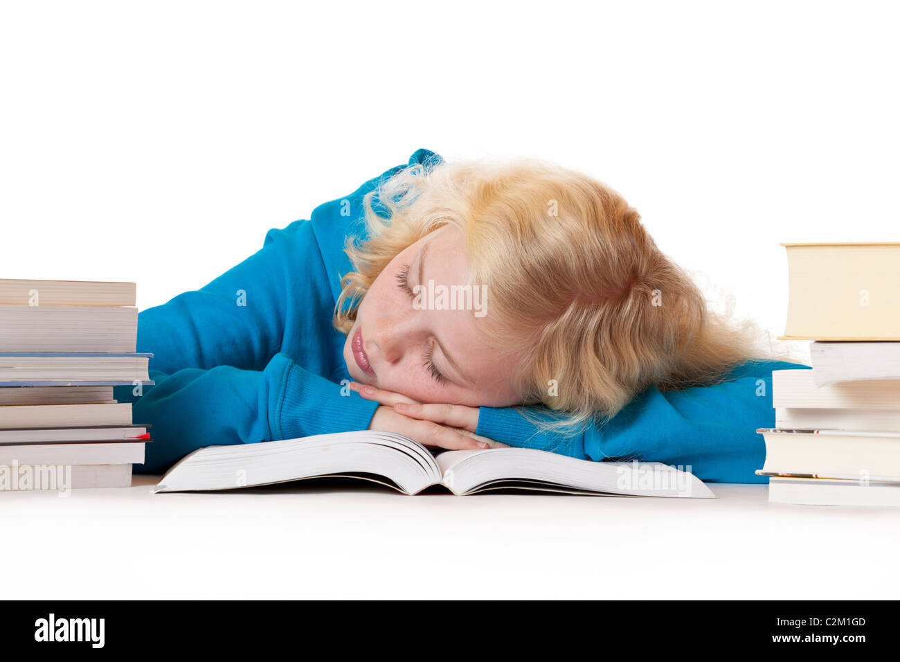 Pretty young blond schoolgirl sleeps on schoolbook.Isolated on white background. Stock Photo