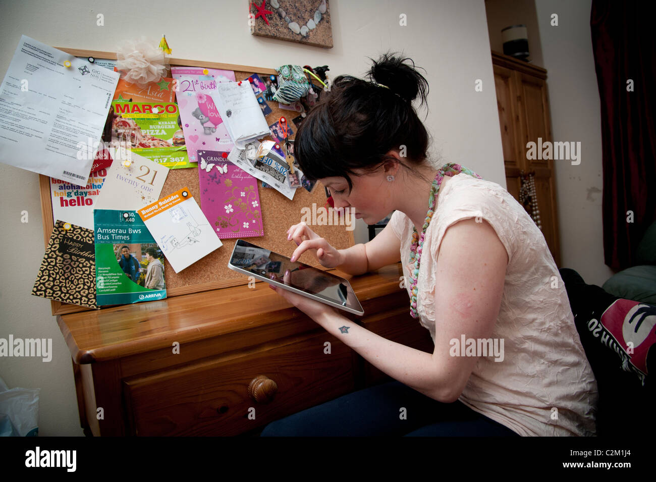 A young woman UK university student using an Apple iPad tablet computer at home Stock Photo