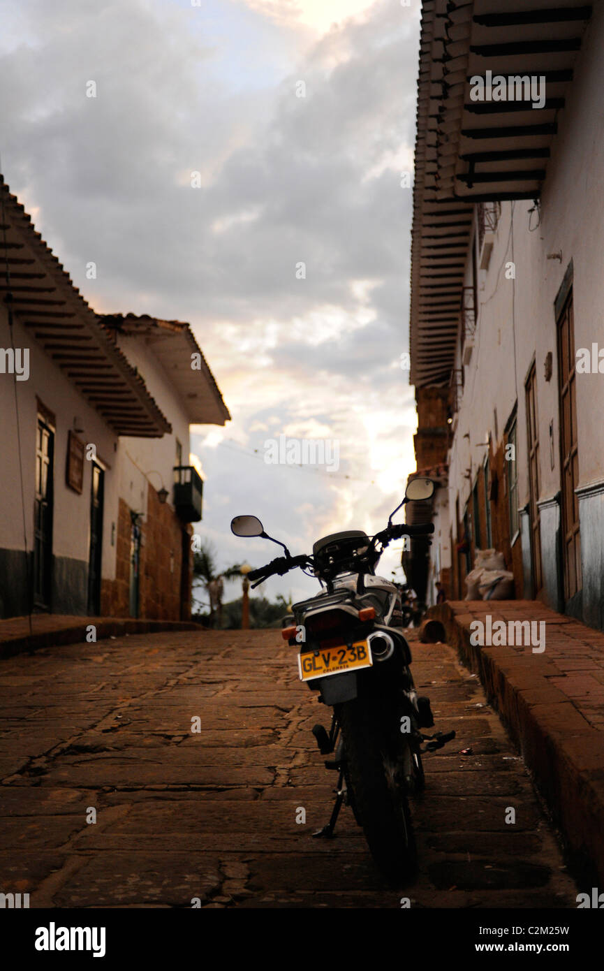 View from uphill cobbled street of a local person's motorbike in the colonial town of Barichara, Colombia Stock Photo