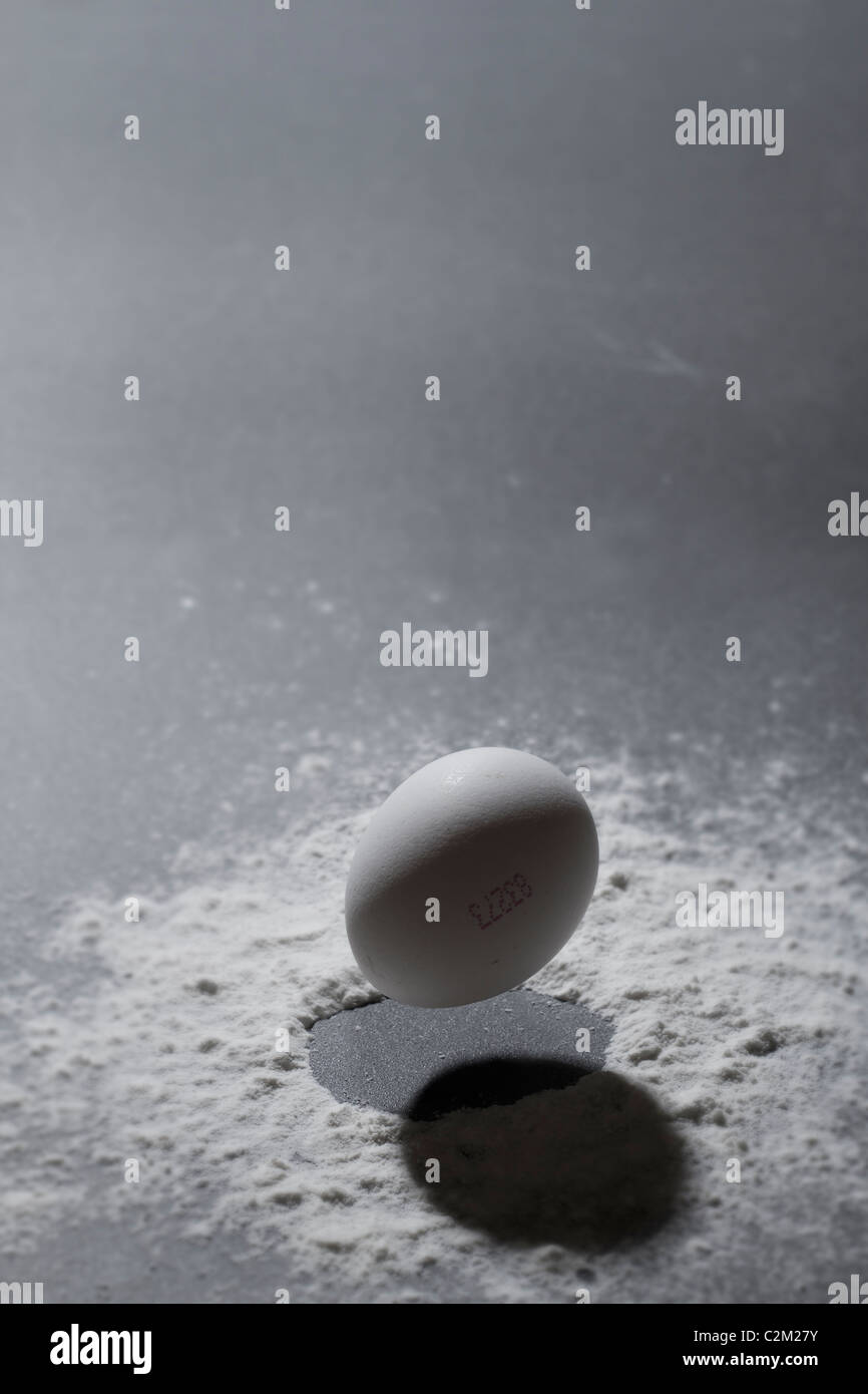 An egg is captured a moment before it crashes onto a table Stock Photo