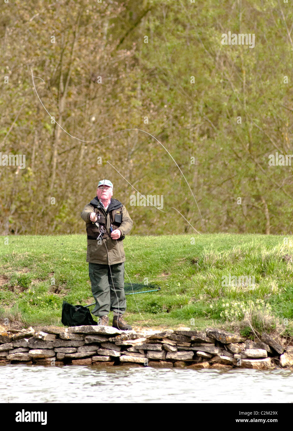 A fly fisherman casting on a trout lake Stock Photo