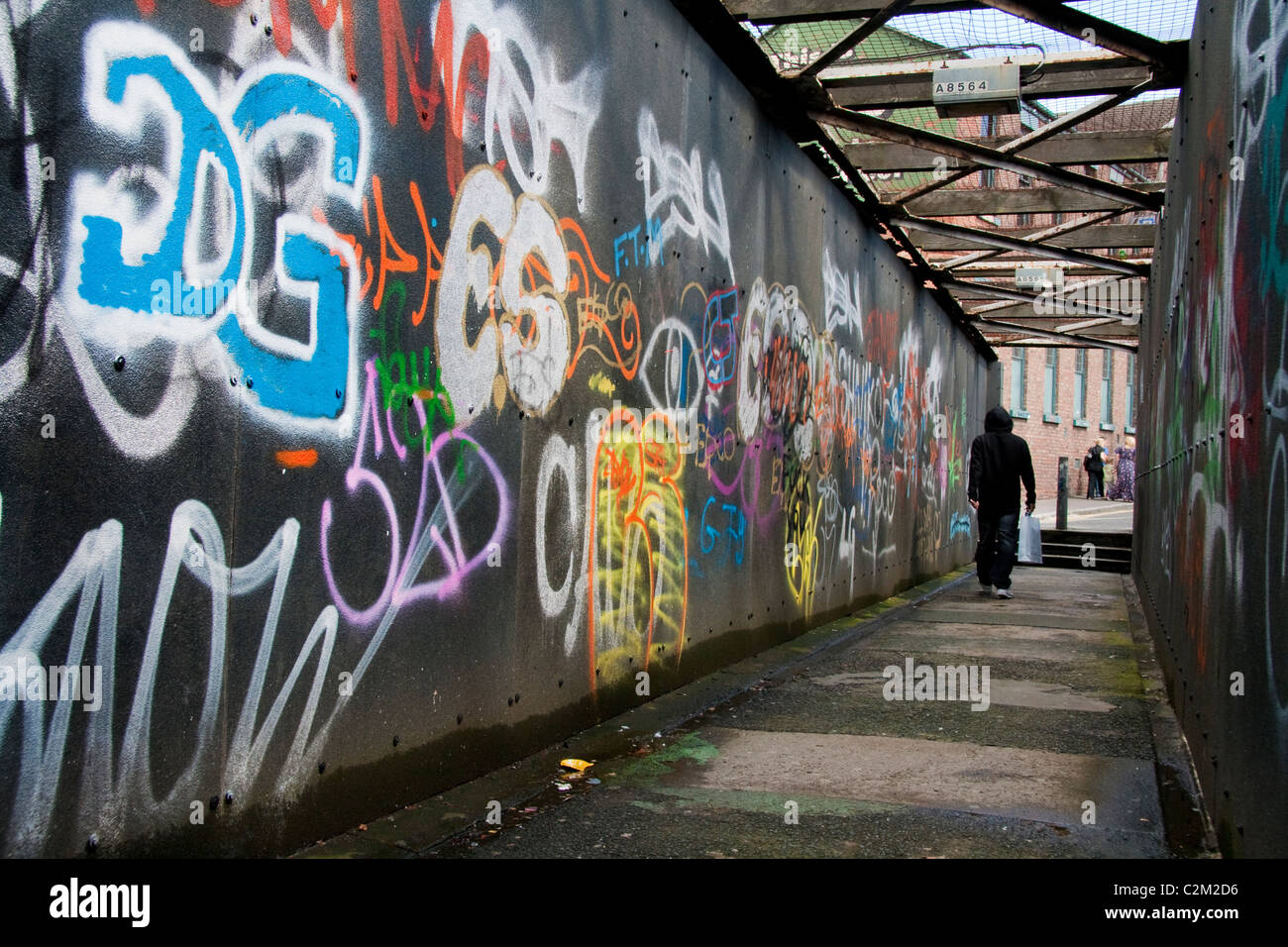 Man walks through a walkway covered in graffiti in Liverpool Stock Photo