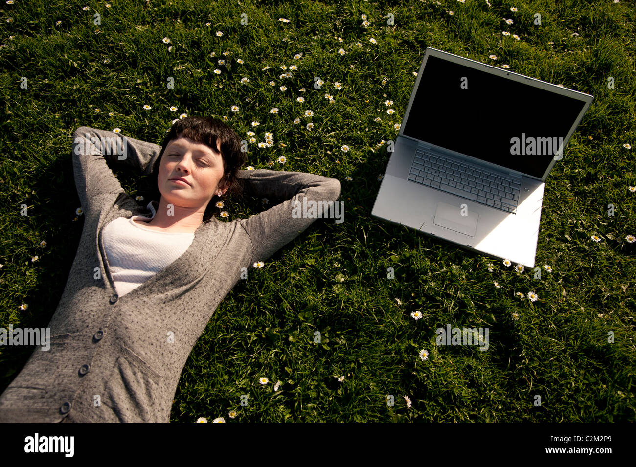 A young woman UK Aberystwyth university student working on her apple laptop computer outdoors on a sunny warm day Stock Photo