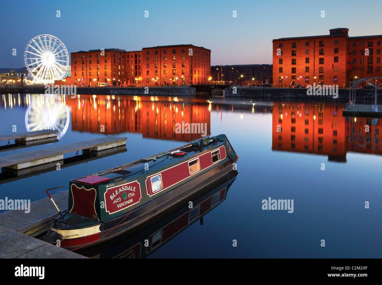 Narrowboat at Salthouse Dock, Liverpool at night with the buildings of the Albert Dock and the Echo Big Wheel in the background Stock Photo