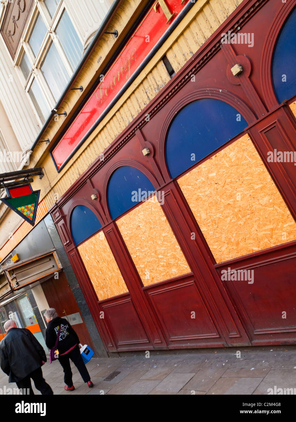 Pedestrians walking past boarded up pool hall in Nottingham City centre England UK Stock Photo