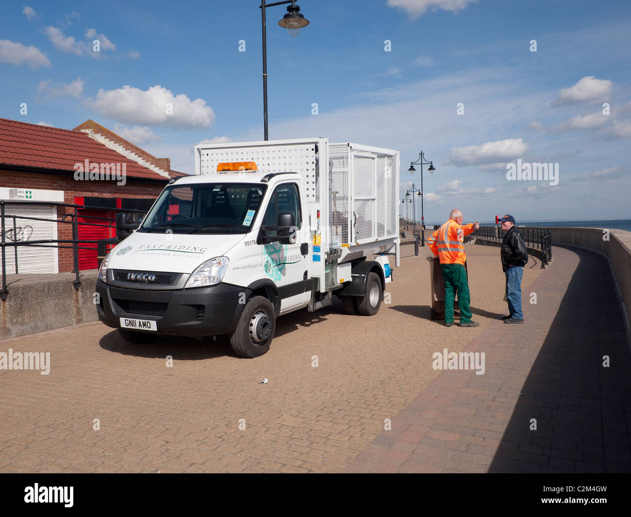 East Riding council worker with a smart white van emptying litter bins on seaside promenade
