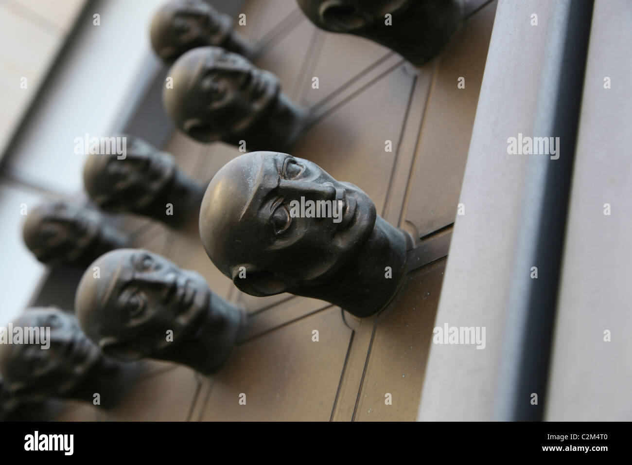Fist-sized bronze heads decorating a 20-foot high door in Nove Mesto district Prague Czech Republic Stock Photo